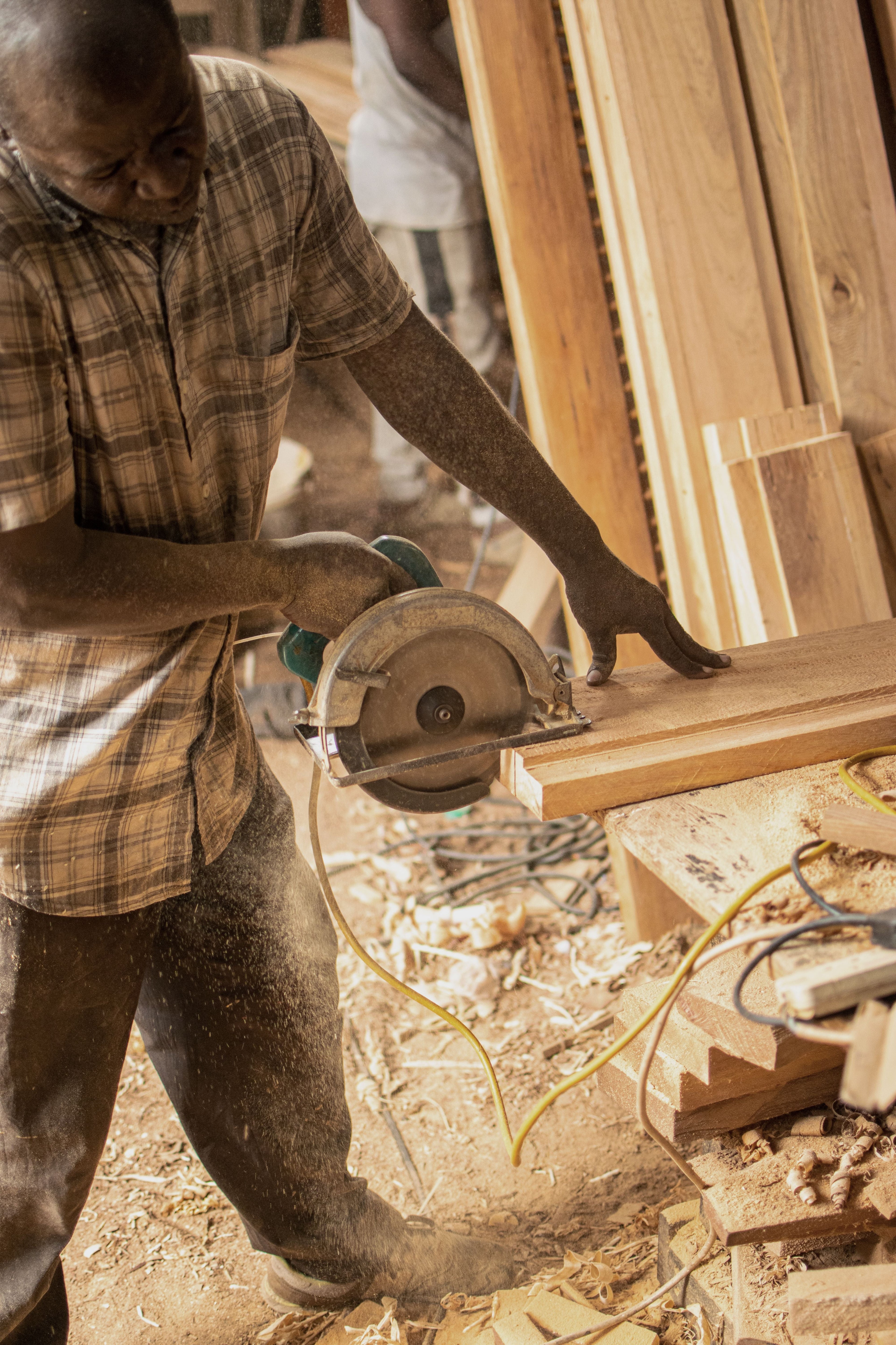 Carpenter using a circular saw while framing a wooden door frame in a workshop